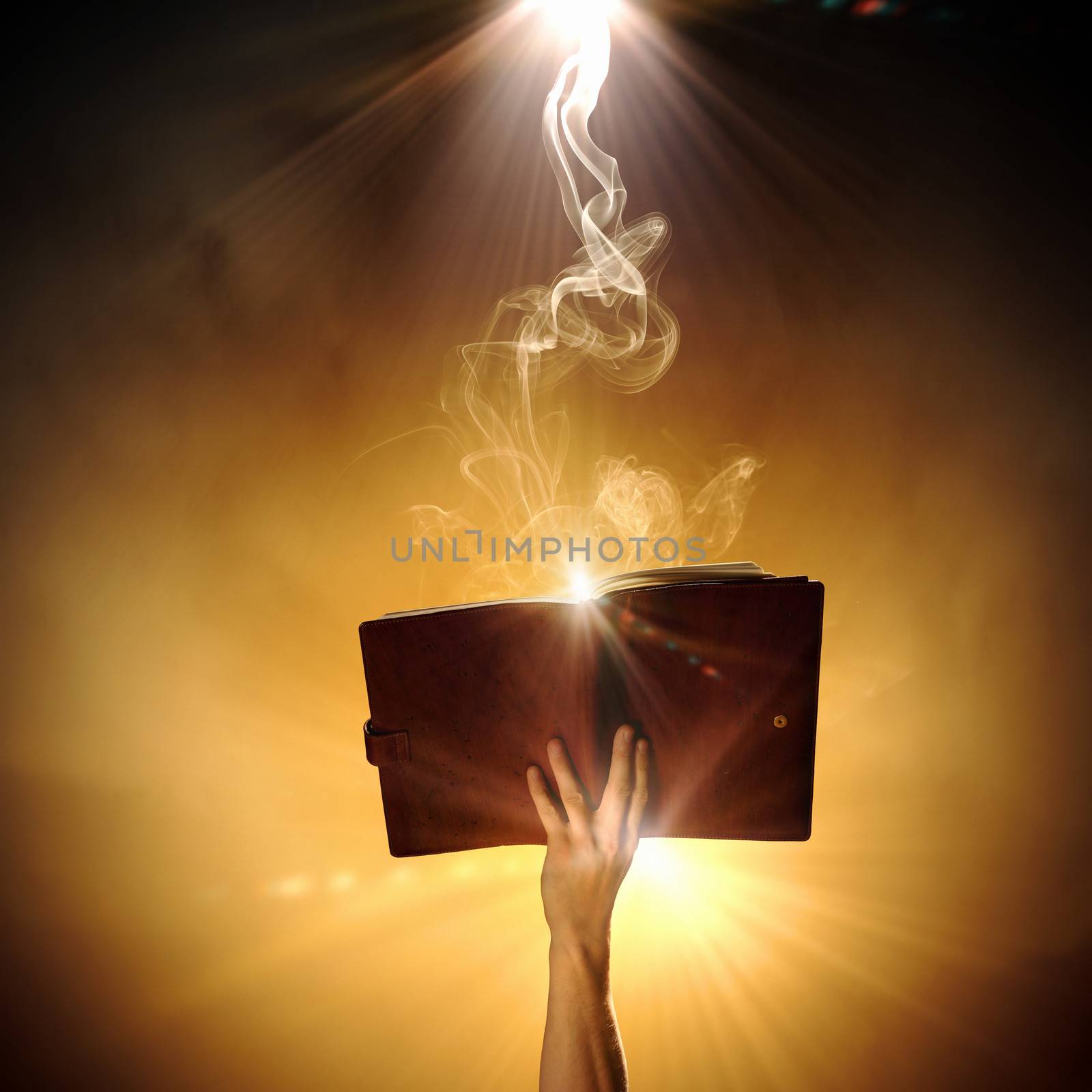 Human hand holding magic book with magic lights