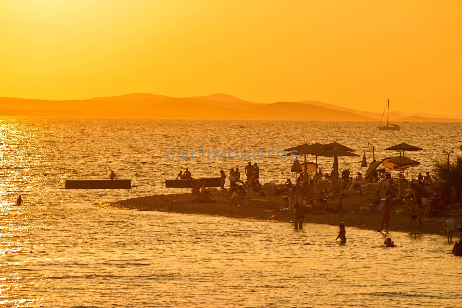 People on the beach silhouettes at golden sunset in Zadar, Croatia