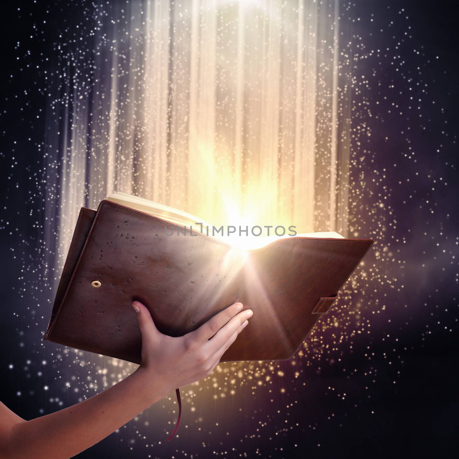 Human hand holding magic book with magic lights