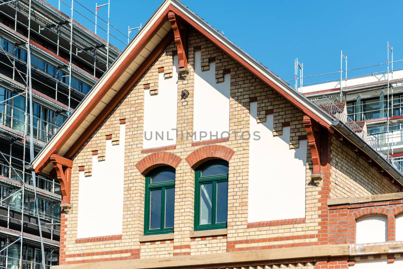 old building in front of modern building with scaffolding on construction site