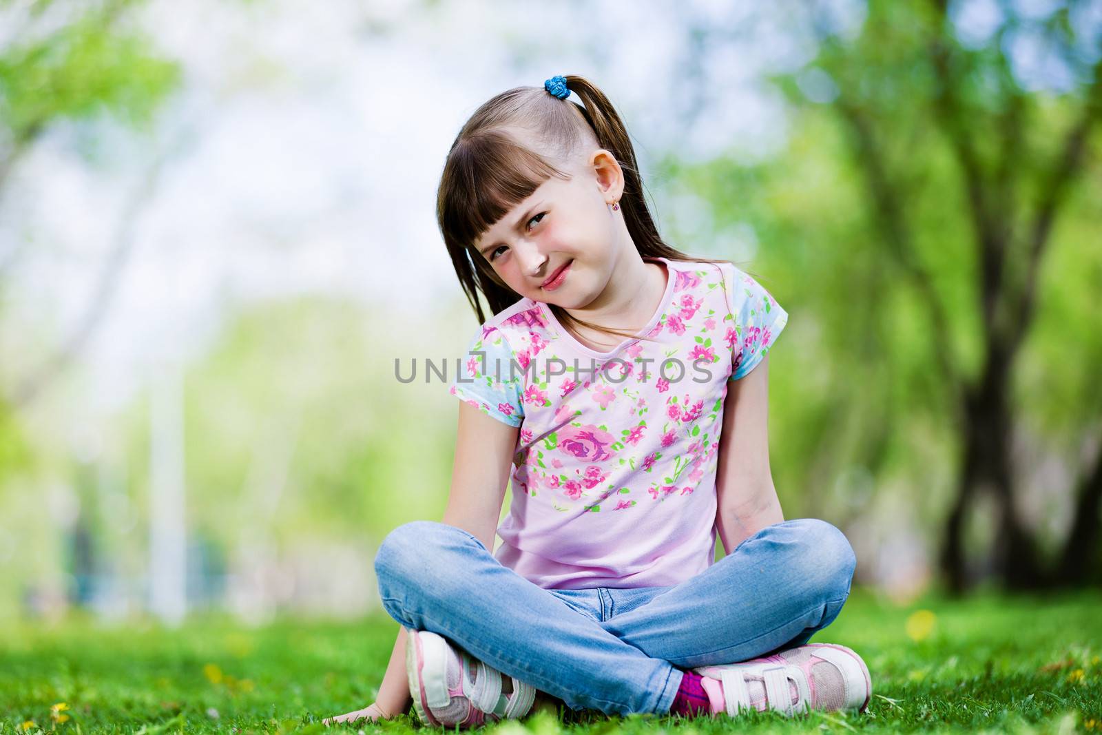 Image of little cute girl sitting on grass in park