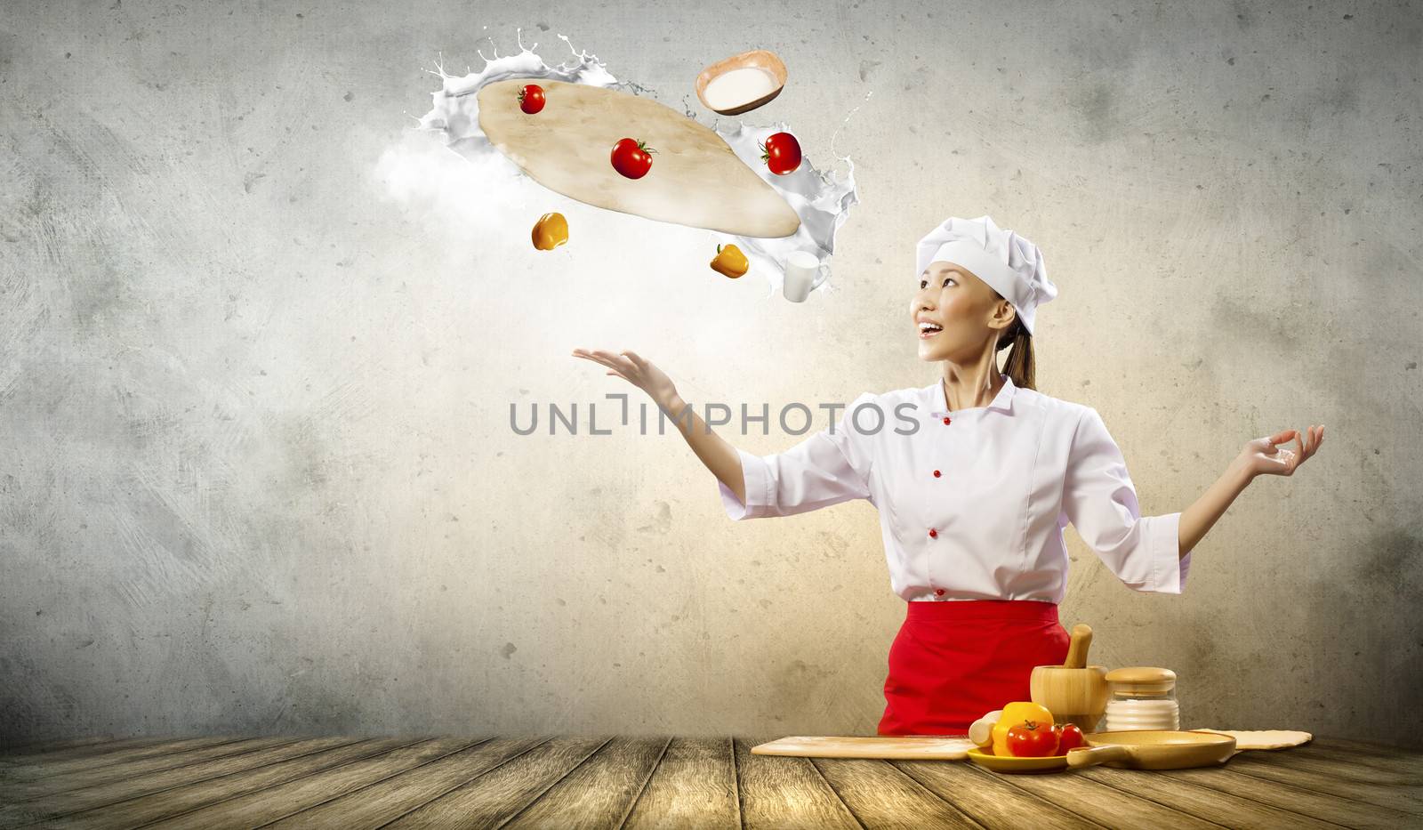 Asian female cook making pizza standing against color background