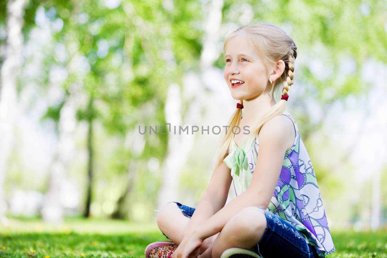 Image of little cute girl sitting on grass in park