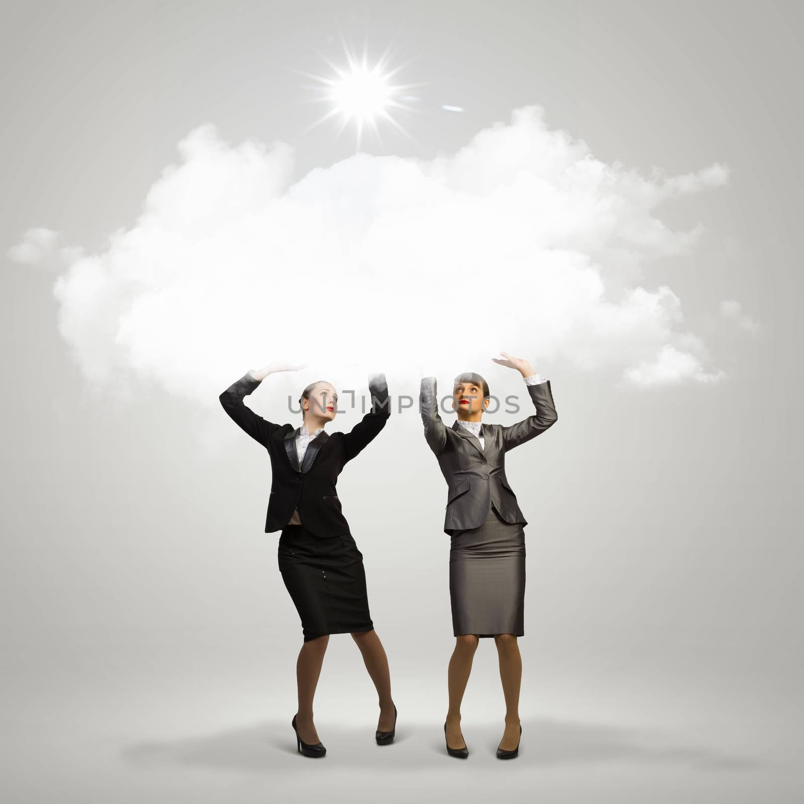 Image of two businesswomen holding clouds above head