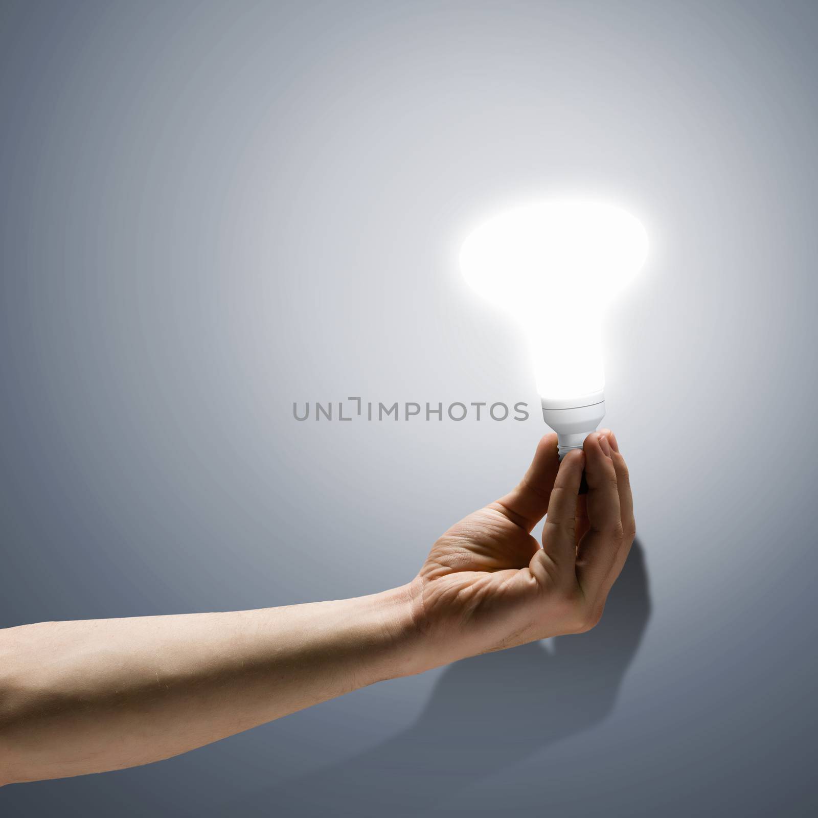 Close up image of human hand holding electrical bulb
