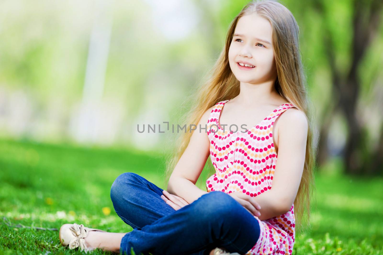 Image of little cute girl sitting on grass in park