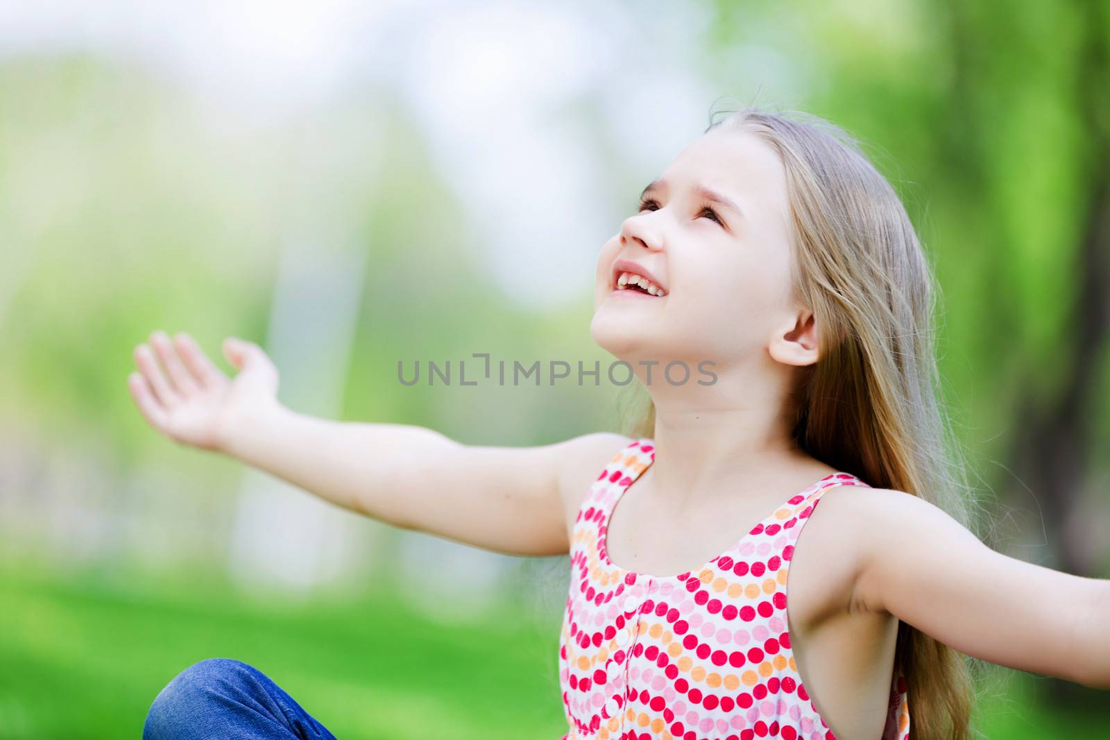 Image of little cute girl sitting on grass in park