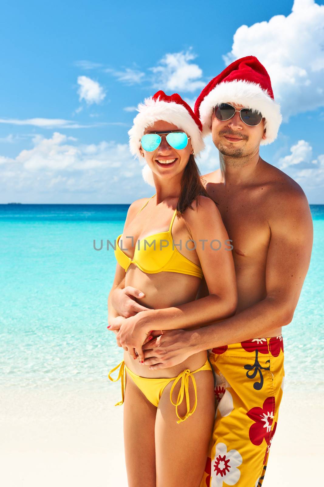 Couple in santa's hat on a tropical beach at Maldives