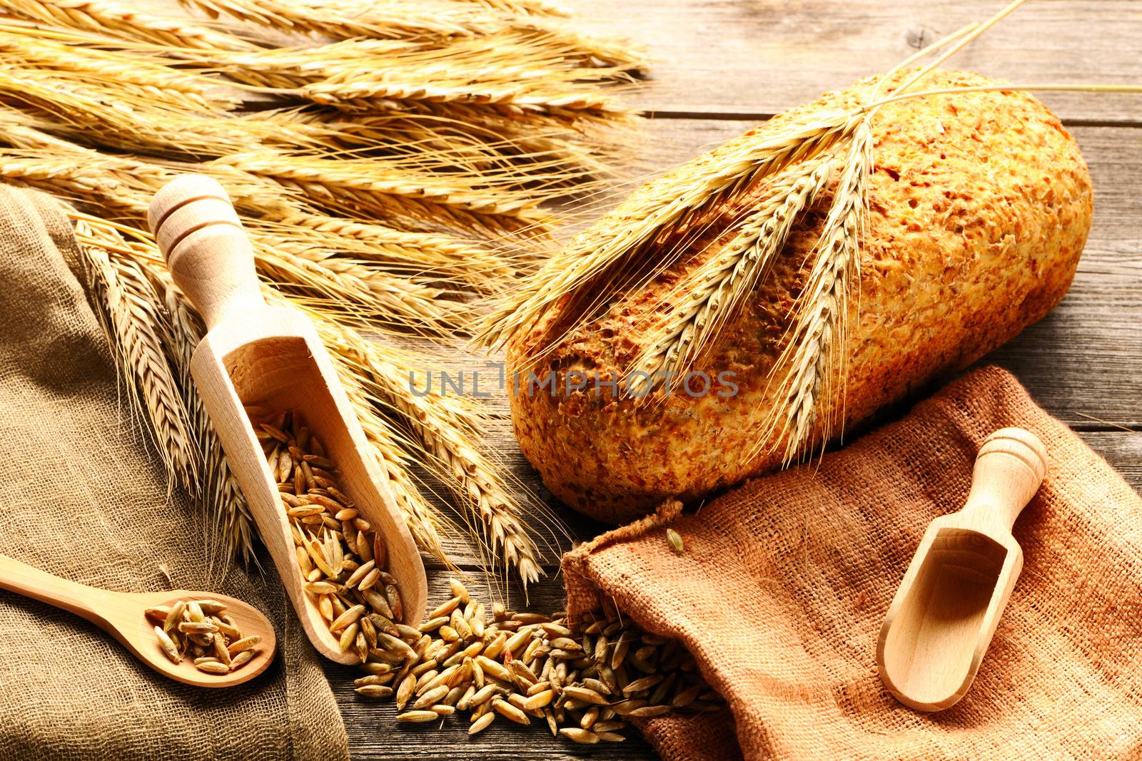 Rye spikelets and bread on wooden background