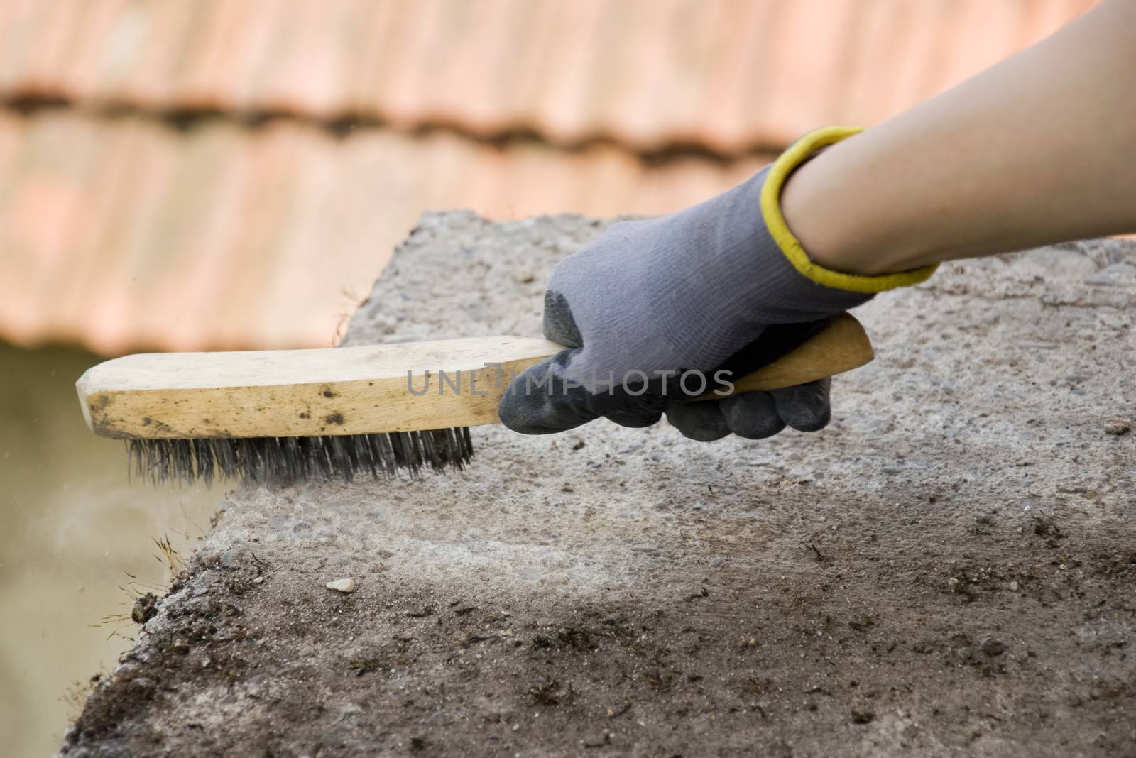 Close-up of woman's hand holding a brush, cleaning concrete  