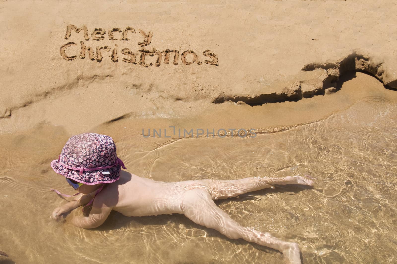 Merry Christmas written in the sand and baby in the water by jelen80