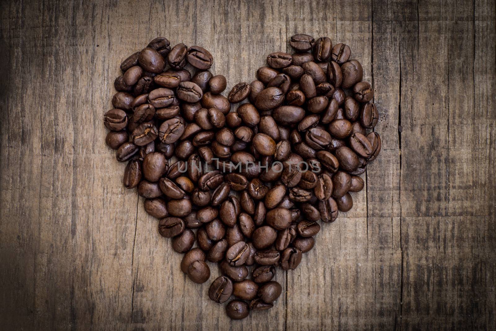A heart shaped out of coffee beans on wood background