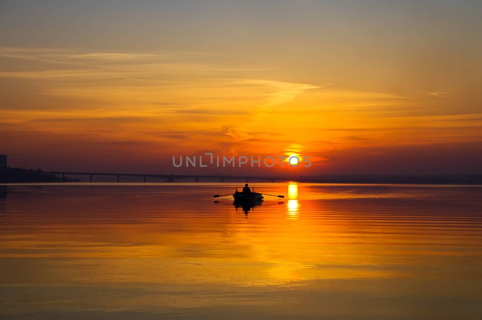 sunset over water surface with small boat by mycola