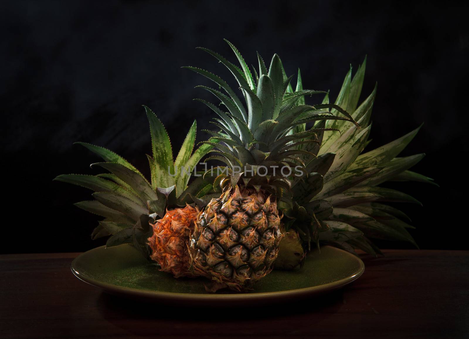 pineapple in ceramic dish with low key light in studio by khunaspix