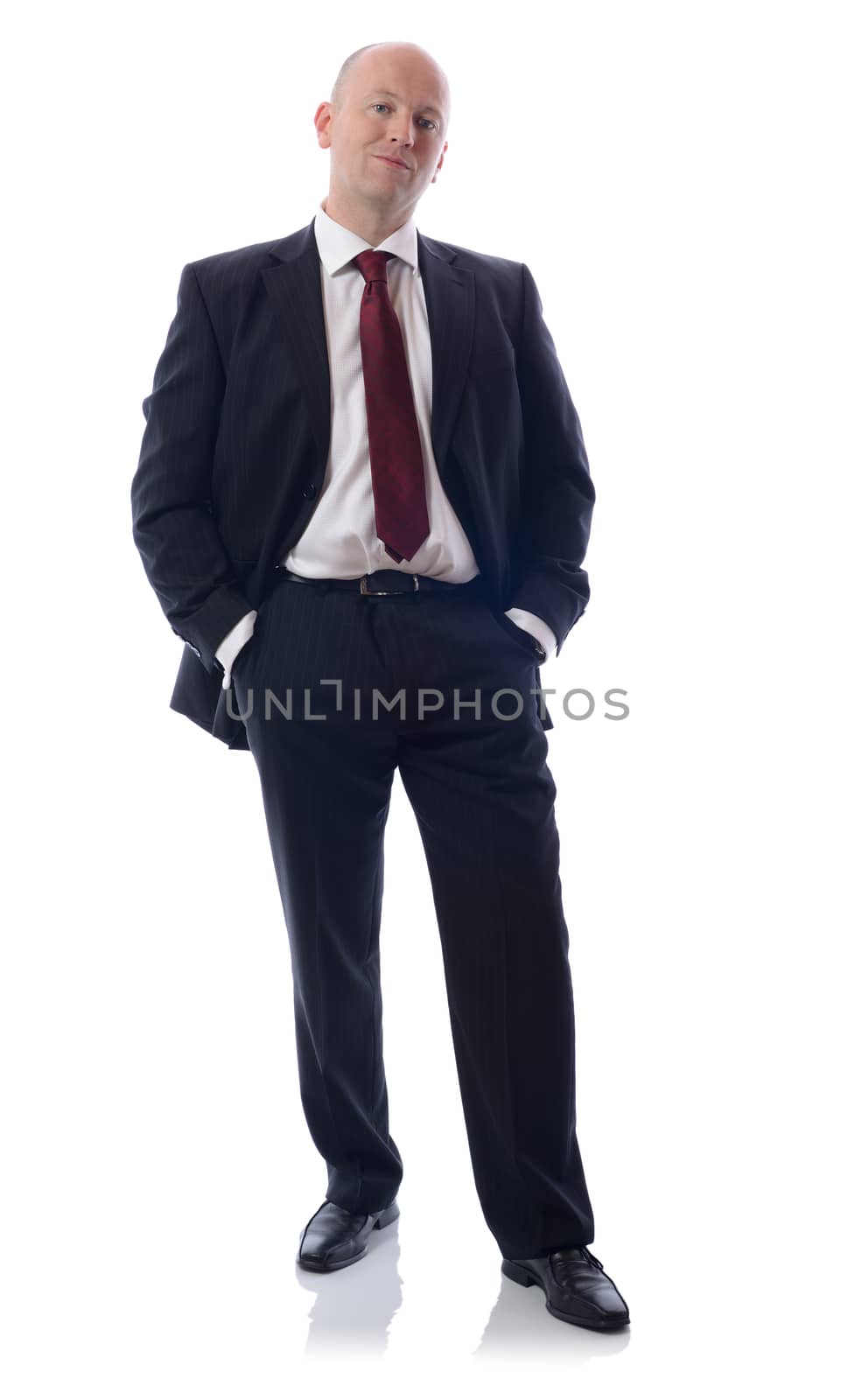 Full length portrait of a young businessman standing with his hands in the pockets. 