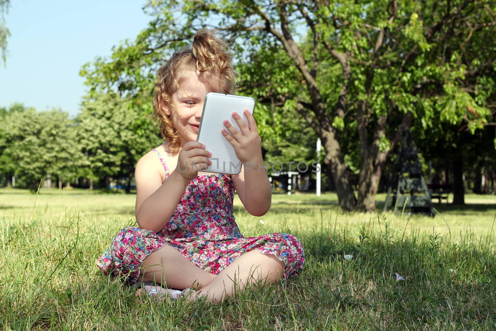 happy little girl with tablet pc in park