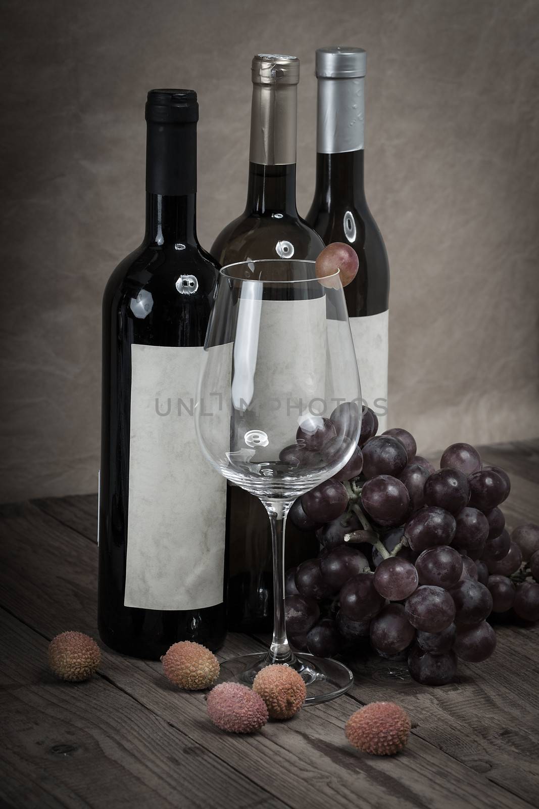 red grapes with wine bottles on wooden background