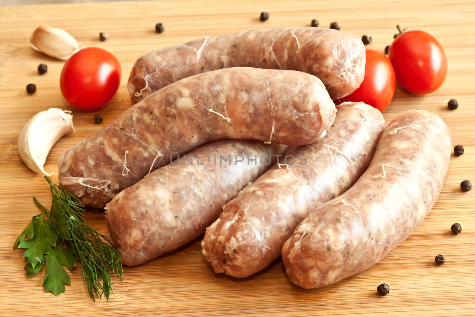 Uncooked sausages with vegetables on the chopping board by evp82
