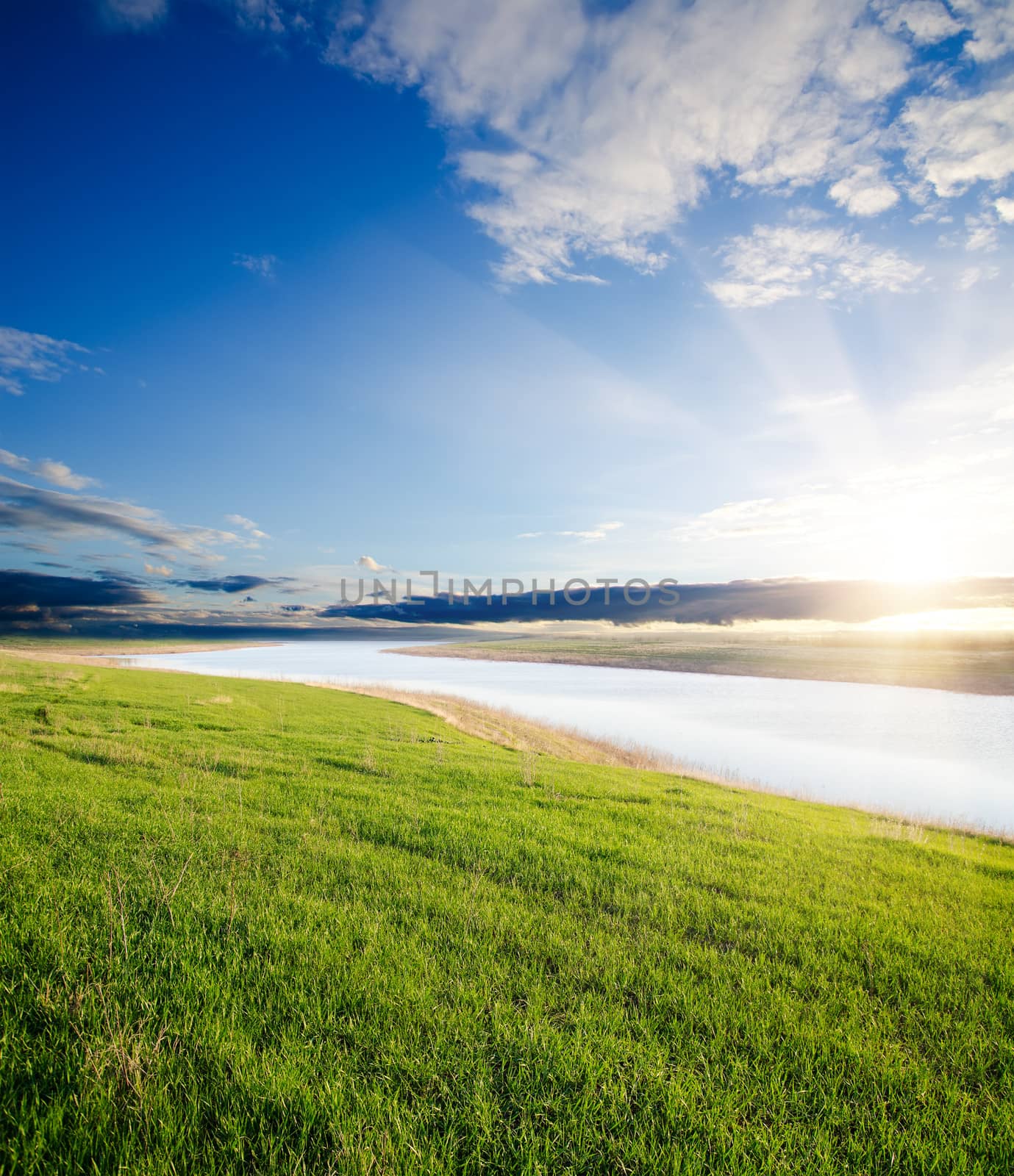 sunset over river and green grass