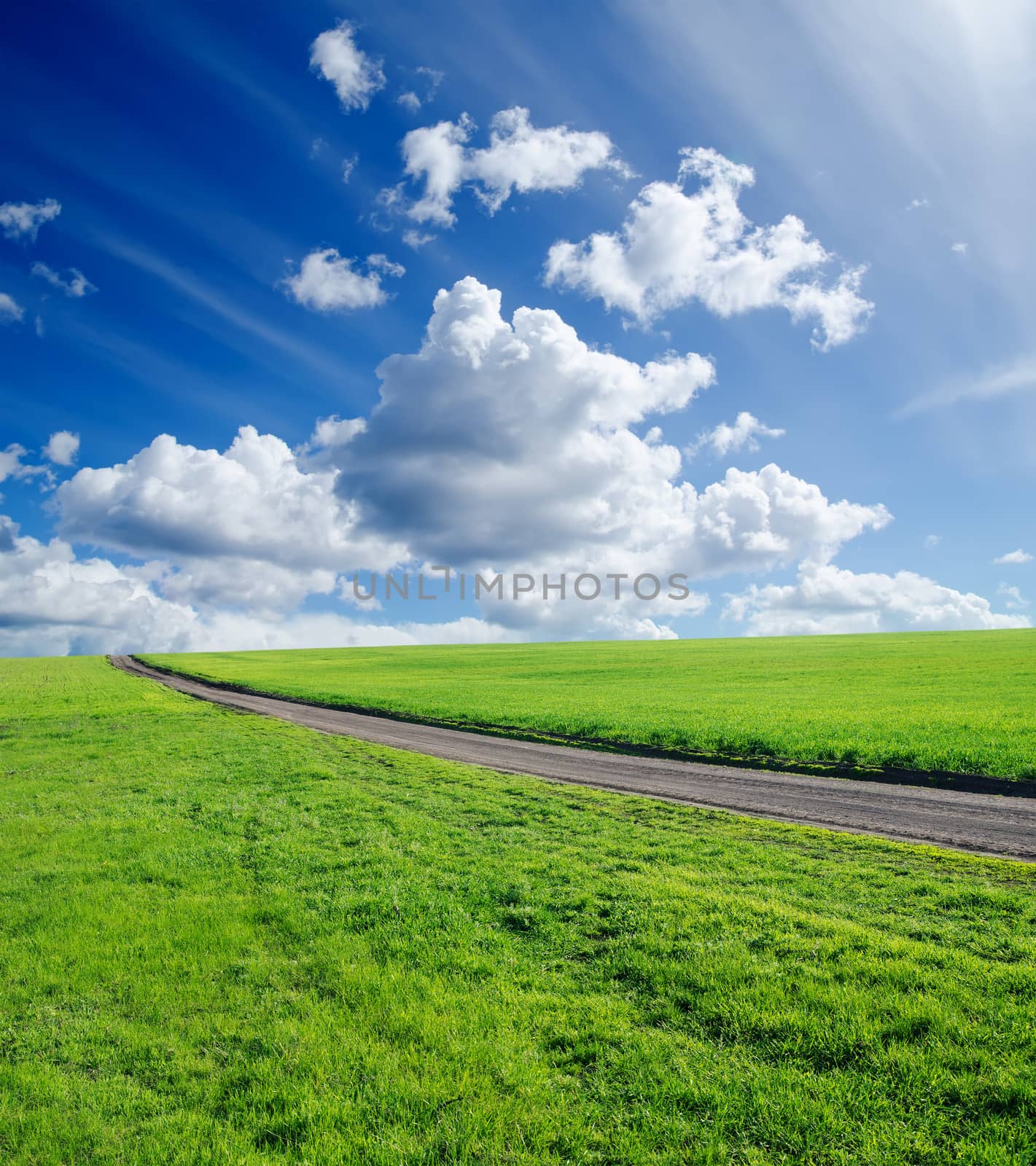 rural road, green grass and cloudy sky