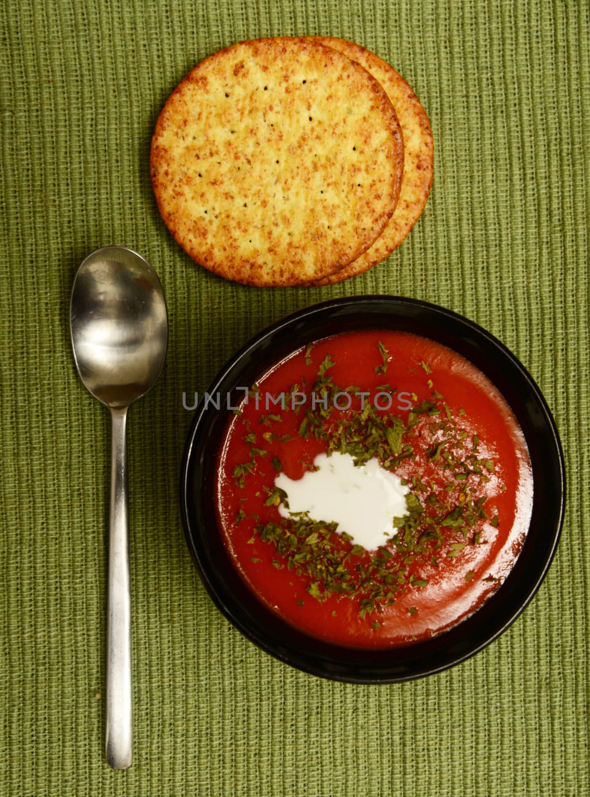 tomato soup on green background with whole grain crackers