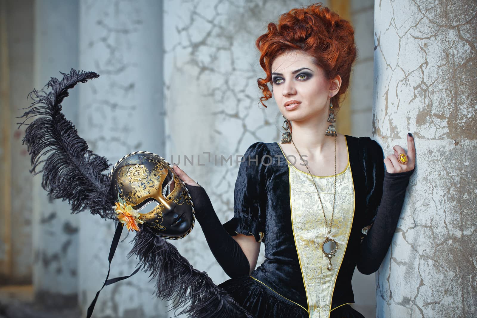 Close-up portrait of red-haired woman holding a mask shot against the background of columns