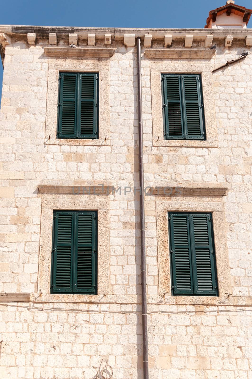 Framed ancient windows with green shutters in a rows.