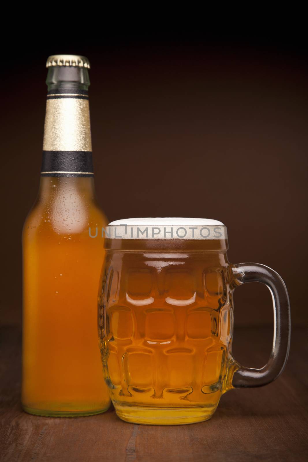 A glass and a bottle of beer on a wooden table.