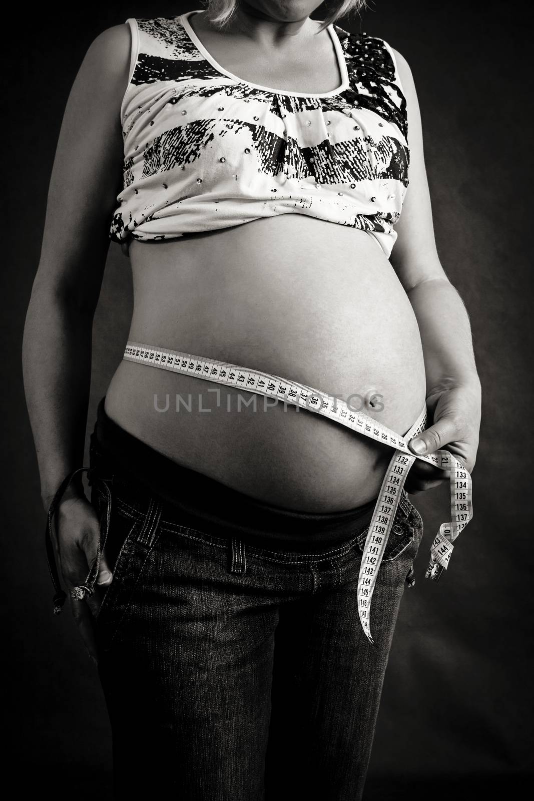 black and white photo of pregnant woman tenderly measuring her tummy