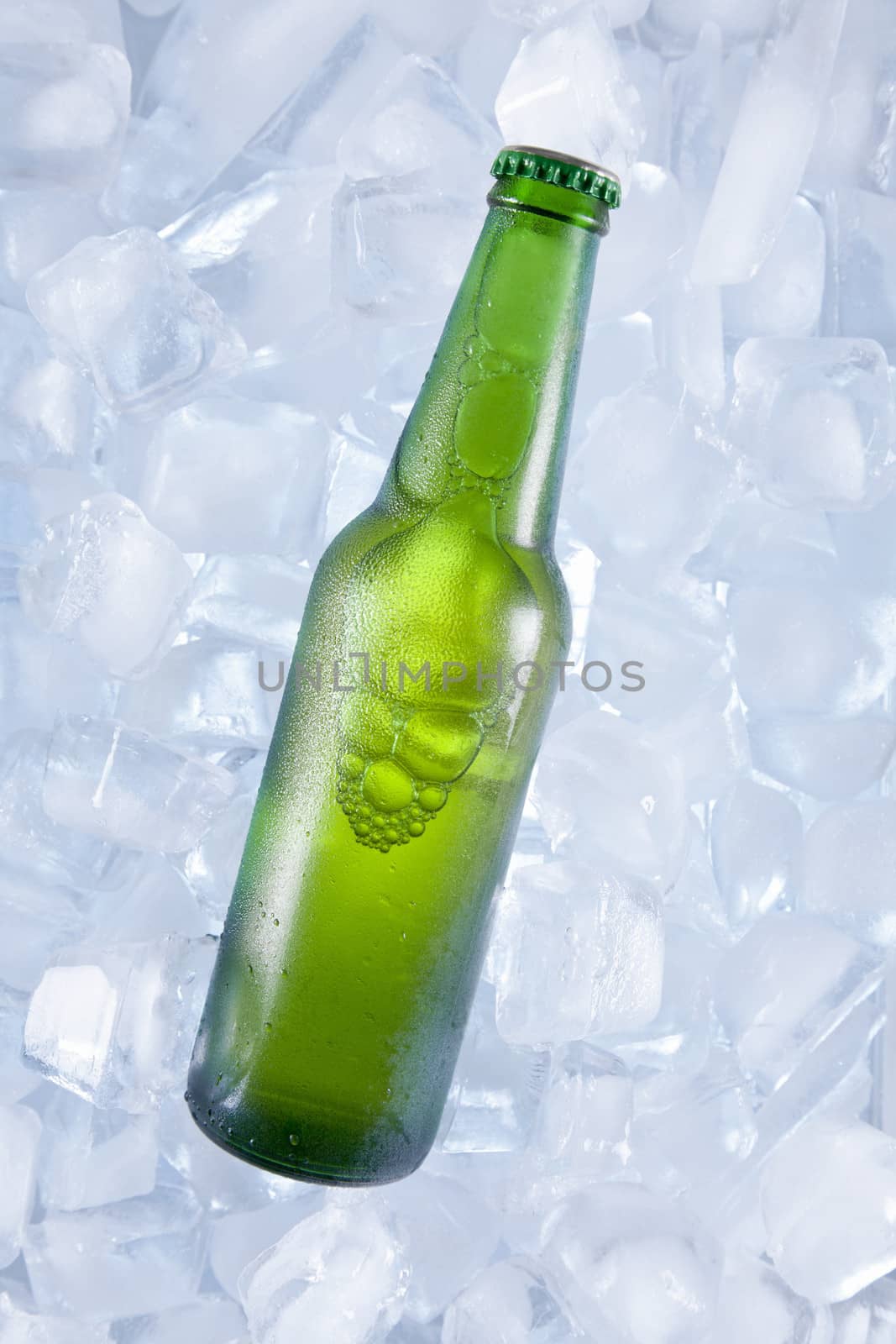 A green bottle of beer on ice.