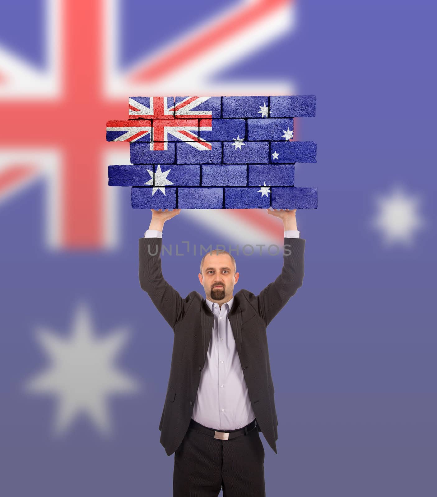 Businessman holding a large piece of a brick wall, flag of Australia, isolated on national flag
