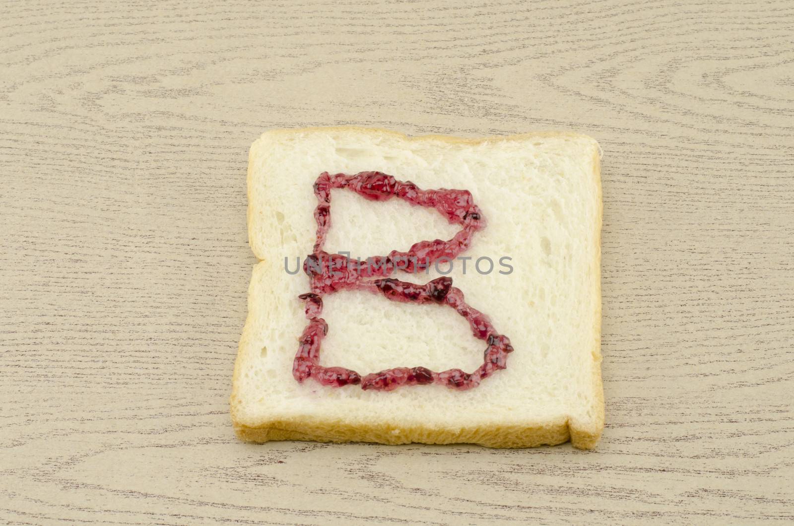 jam alphabet on sliced bread on wood background