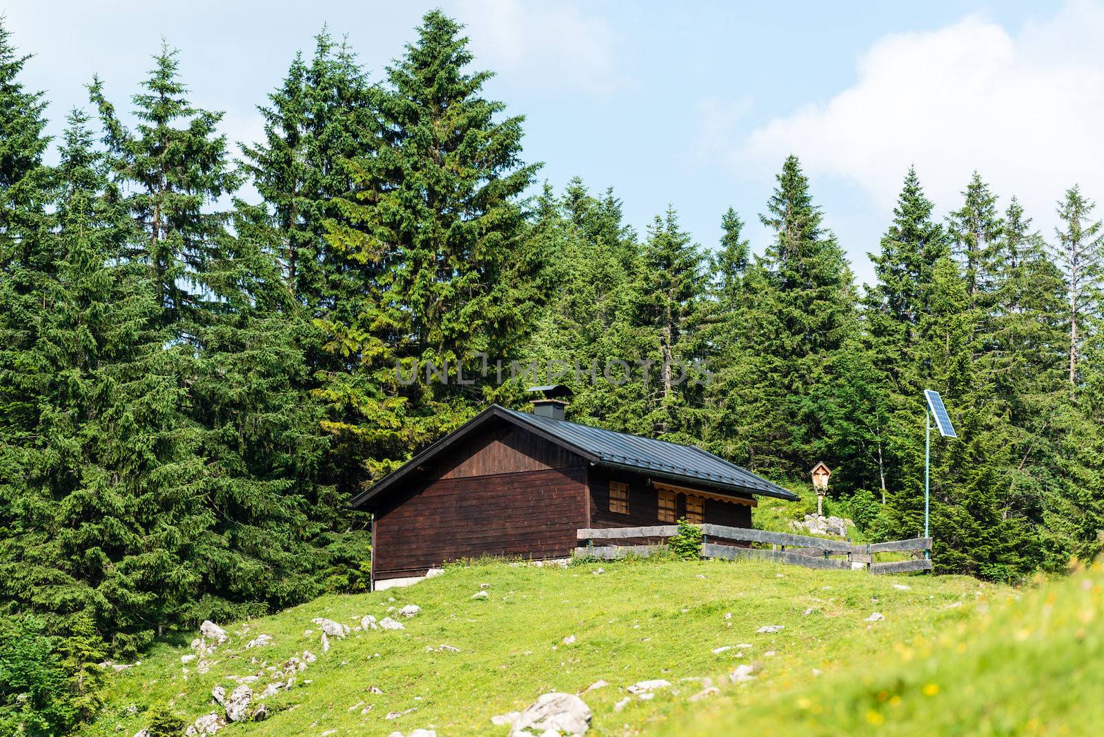 Wooden mountain refuge with solar panels and display of a holy figure in the Bavarian Alps