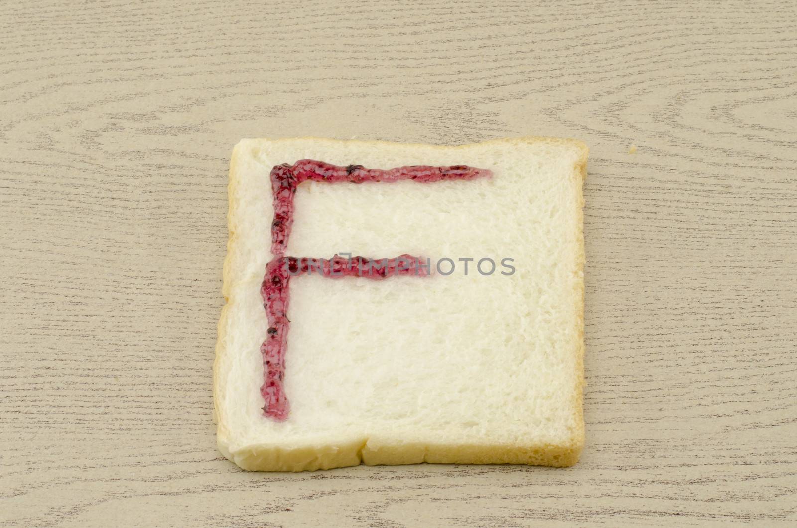 jam alphabet on sliced bread on wood background