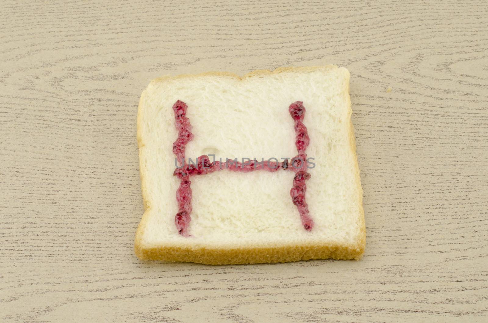 jam alphabet on sliced bread on wood background