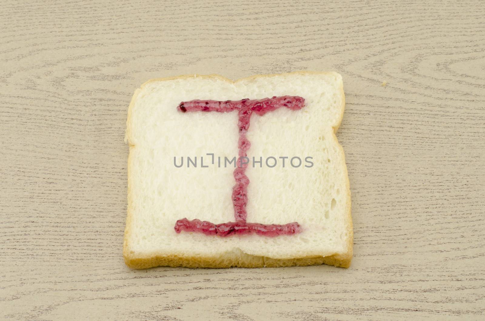 jam alphabet on sliced bread on wood background