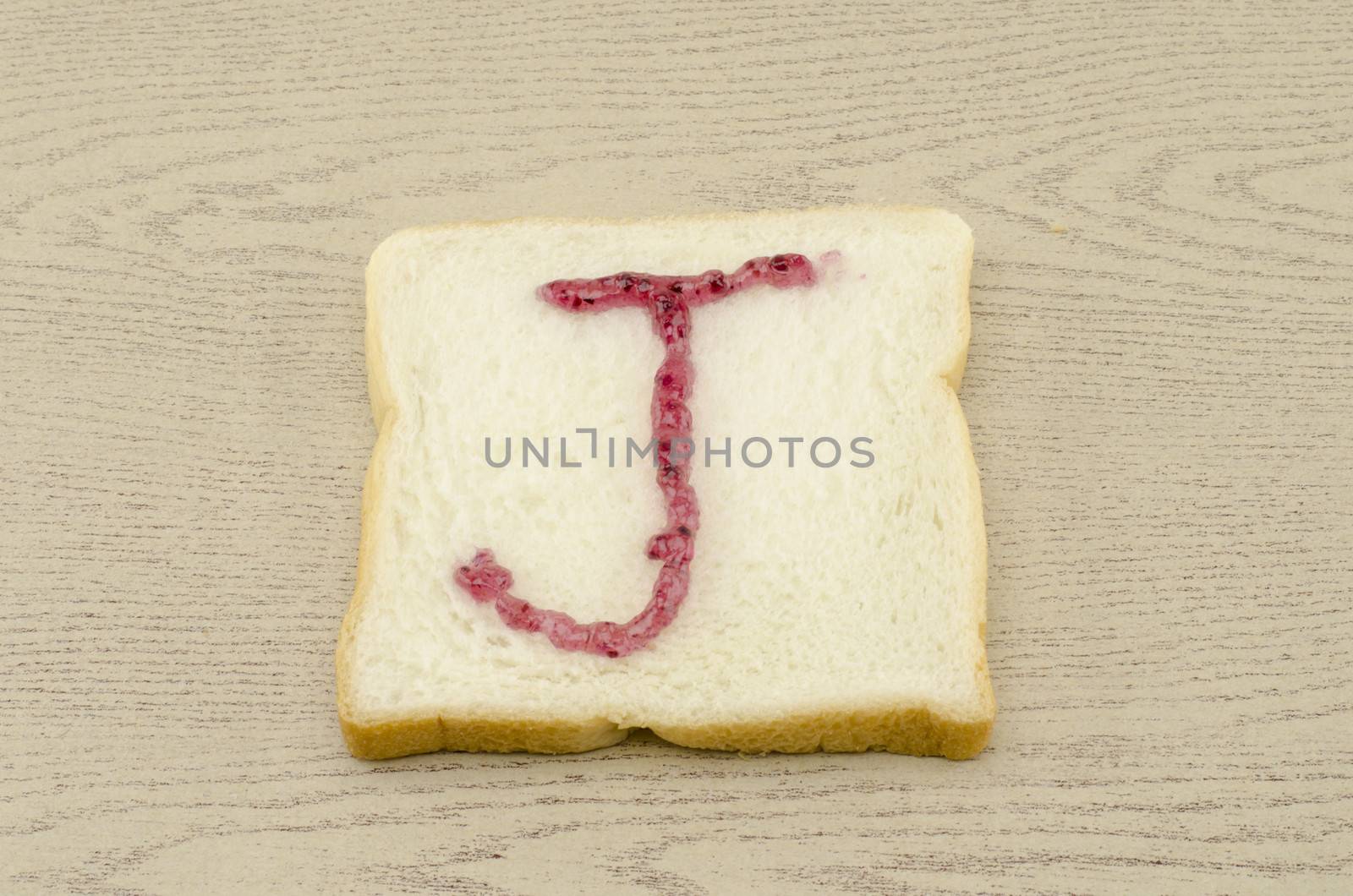 jam alphabet on sliced bread on wood background