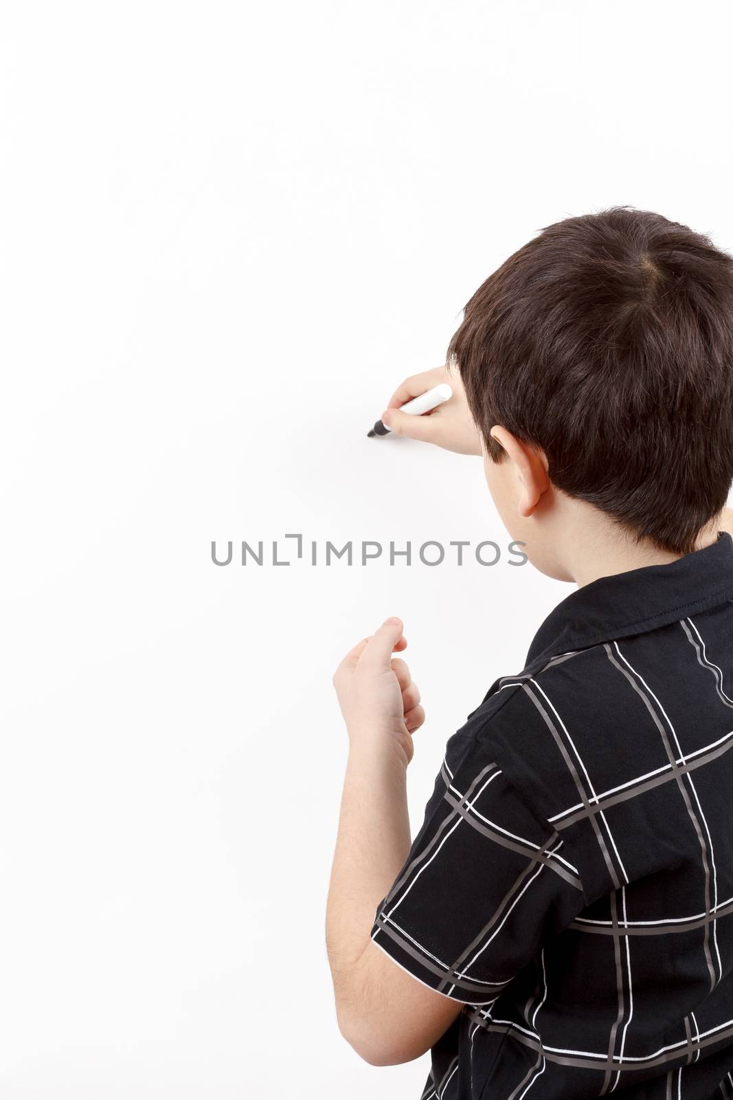 young boy student in a classroom writing on a empty whiteboard