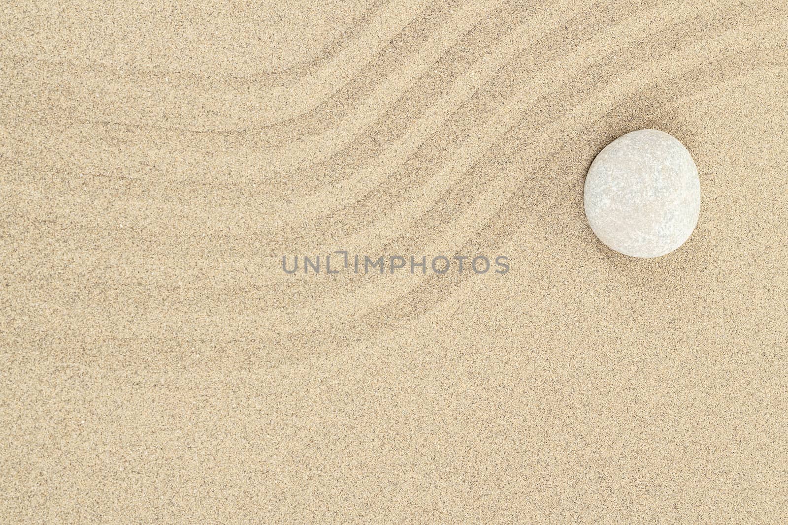 zen stone in soft sand with lines