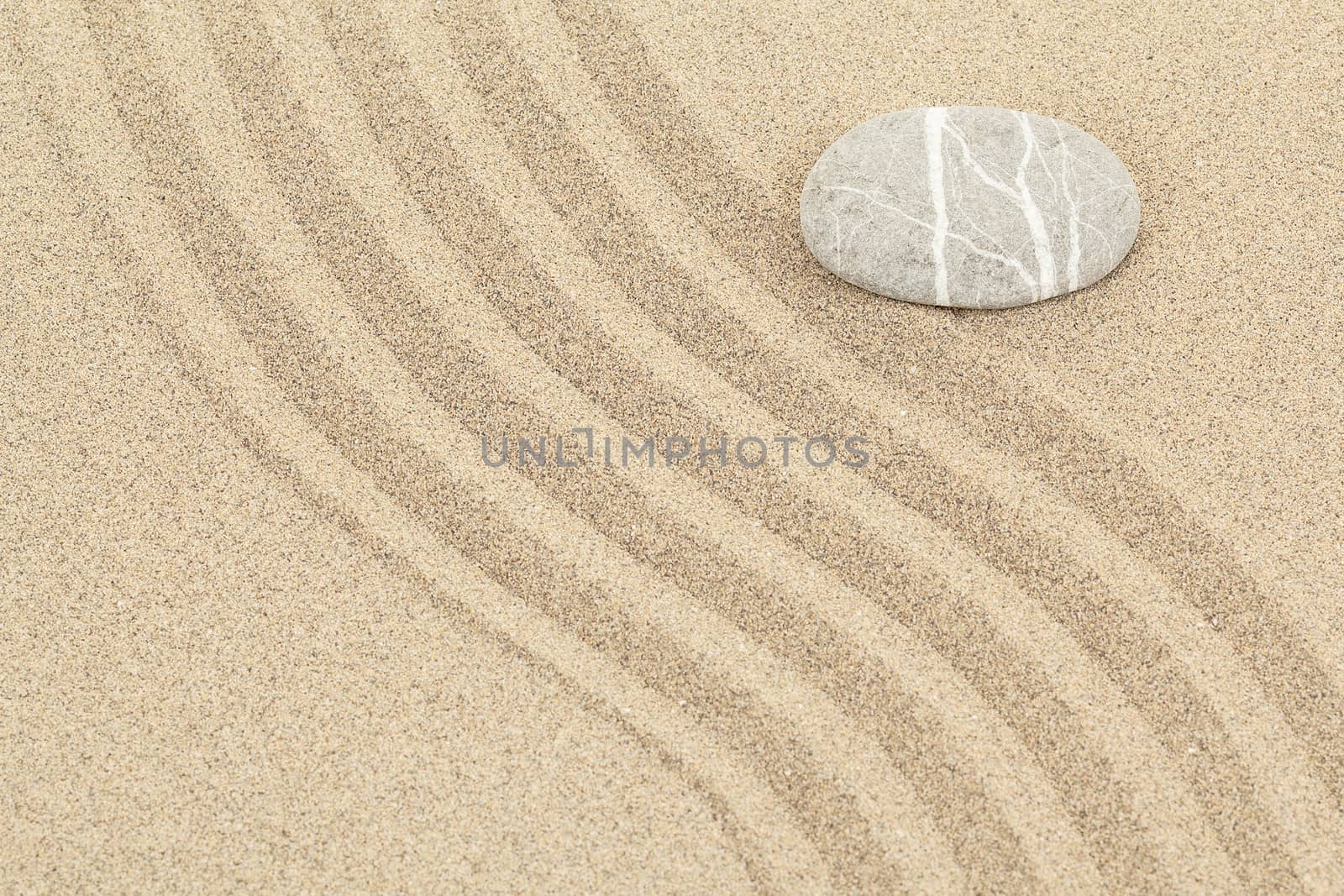 zen stone in soft sand with lines