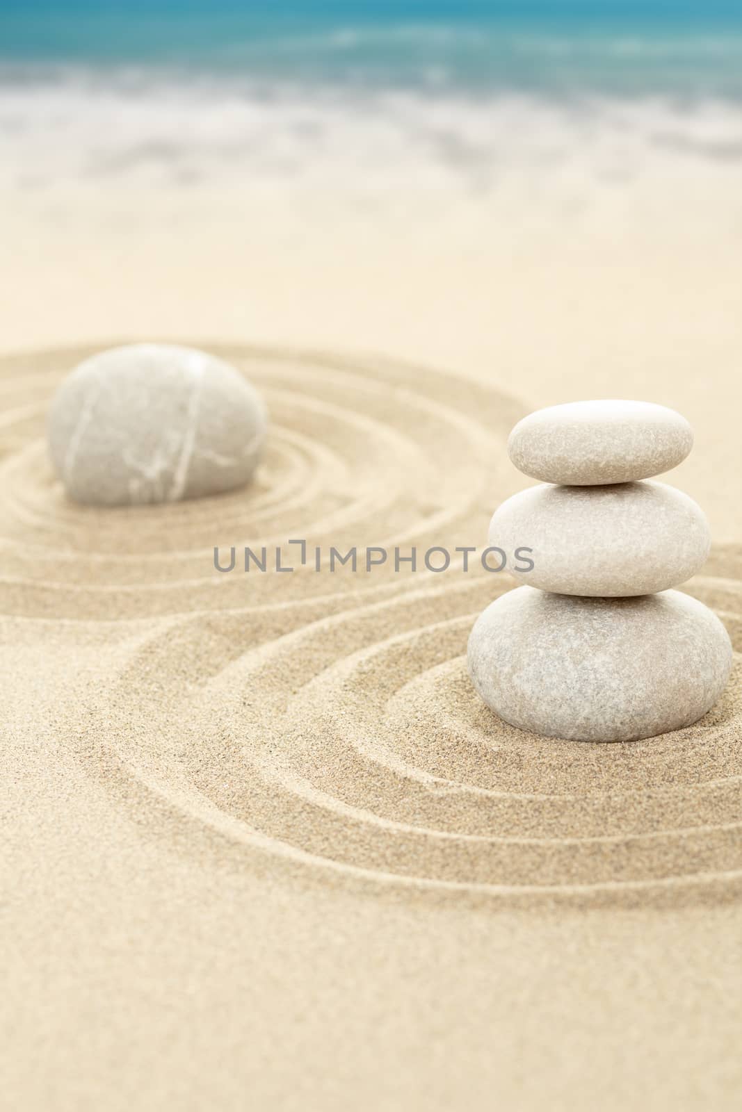 Balance zen stones in sand with sea in background