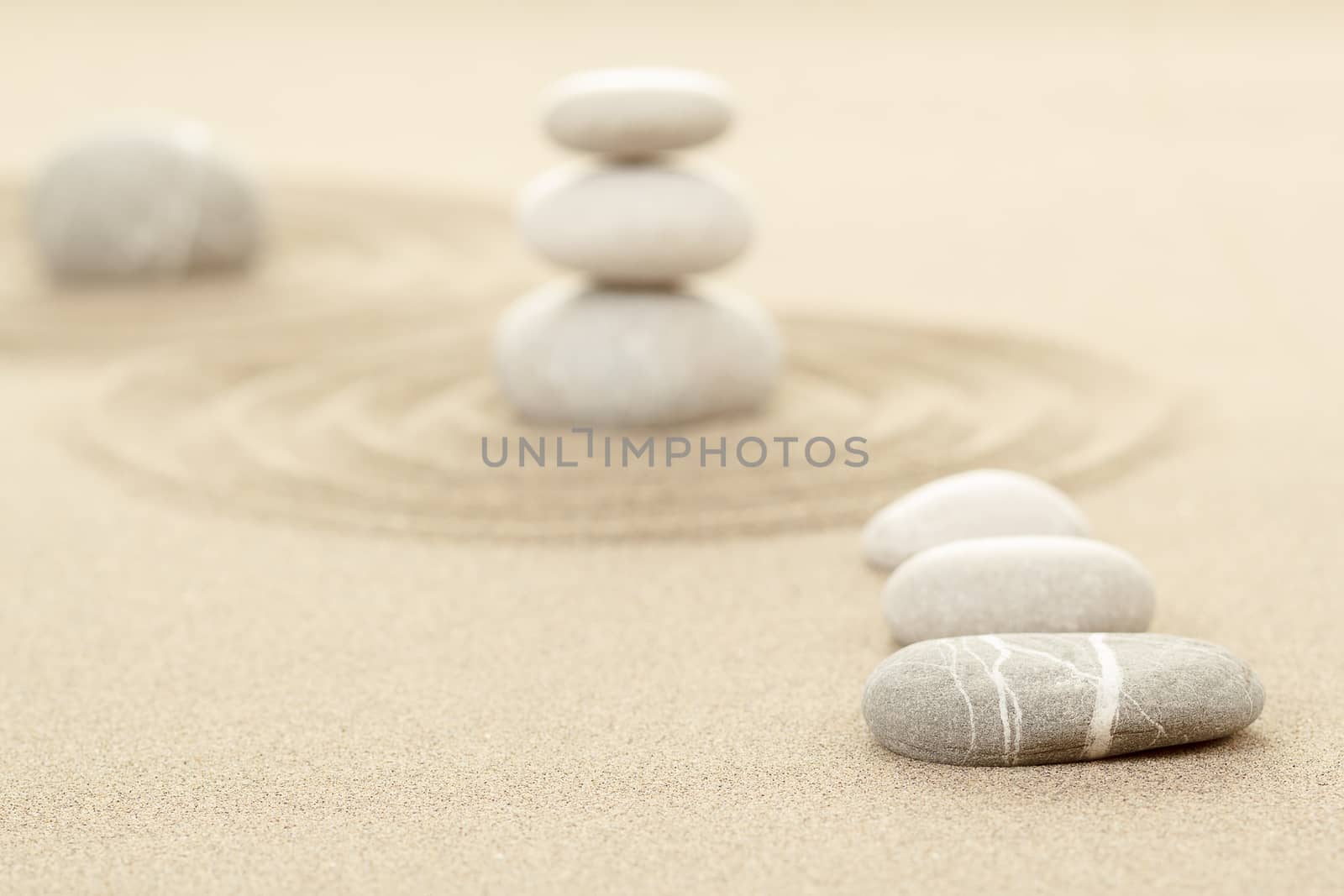 Balance of three zen stones in sand with shallow focus
