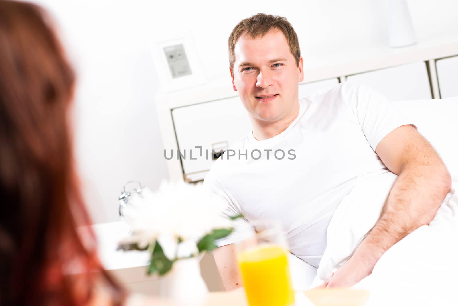 woman brought her boyfriend breakfast in bed, holding a tray of juice and breakfast