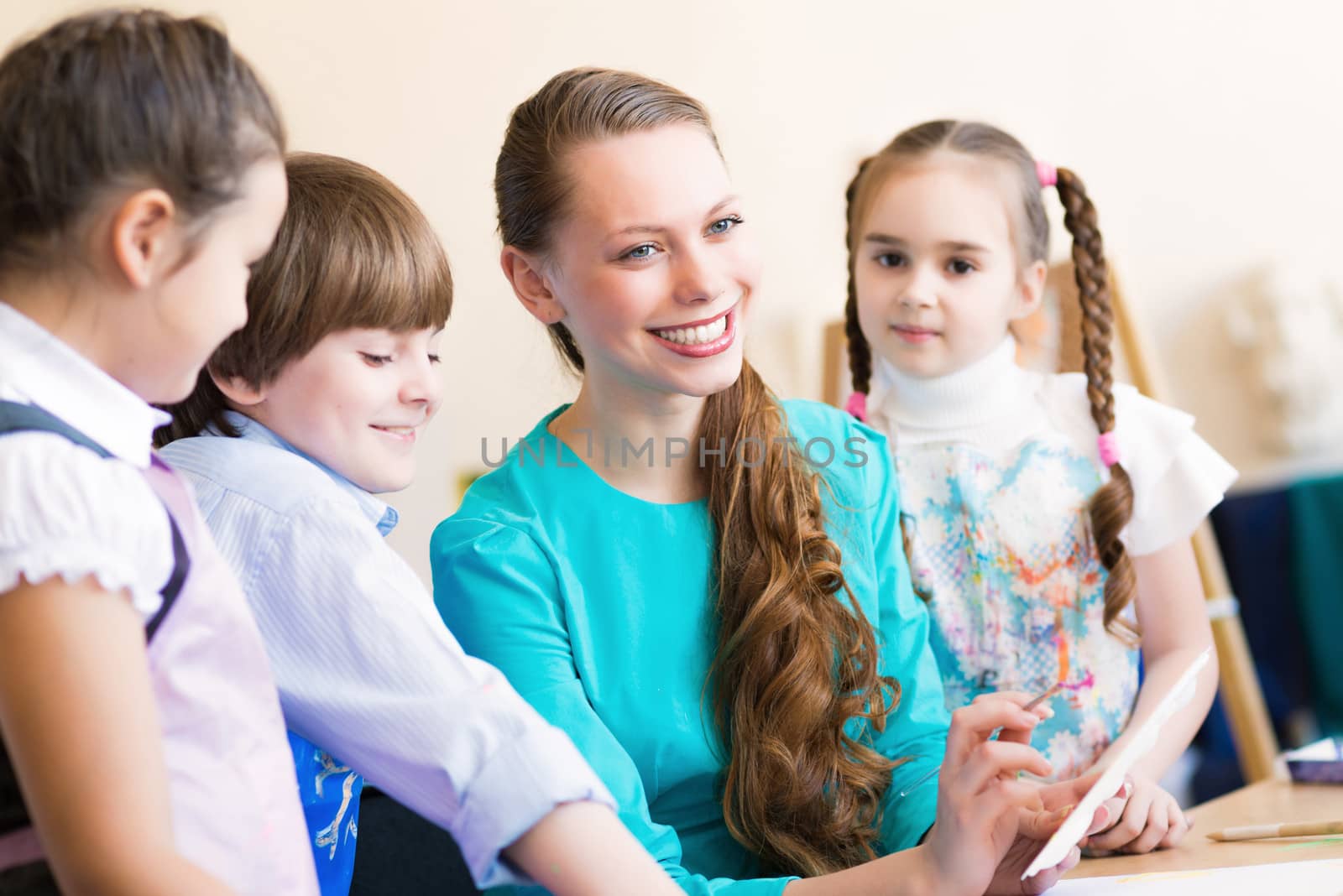 children with the teacher engaged in painting at an art school