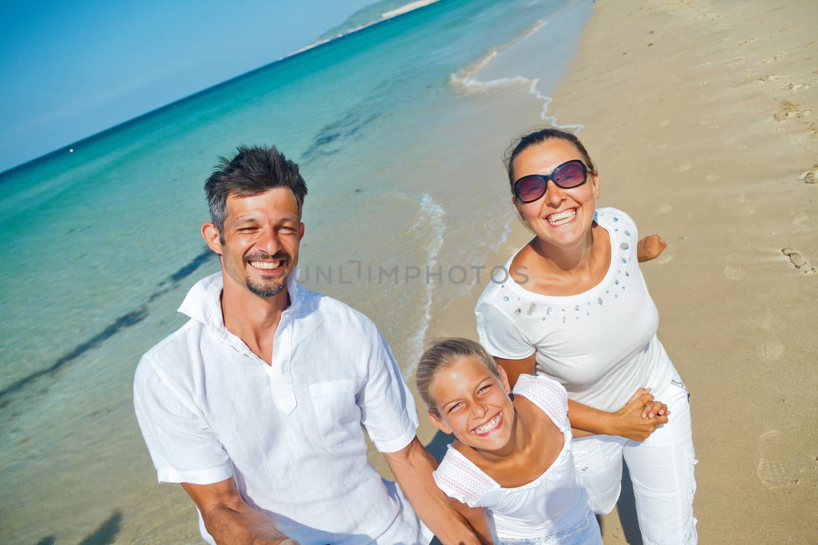 Photo of happy family running on the beach