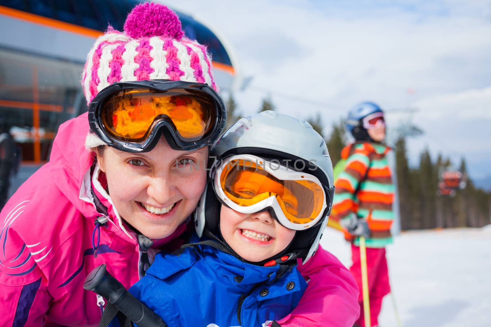 Portrait closeup of happy smiling boy in ski goggles and a helmet with his mother