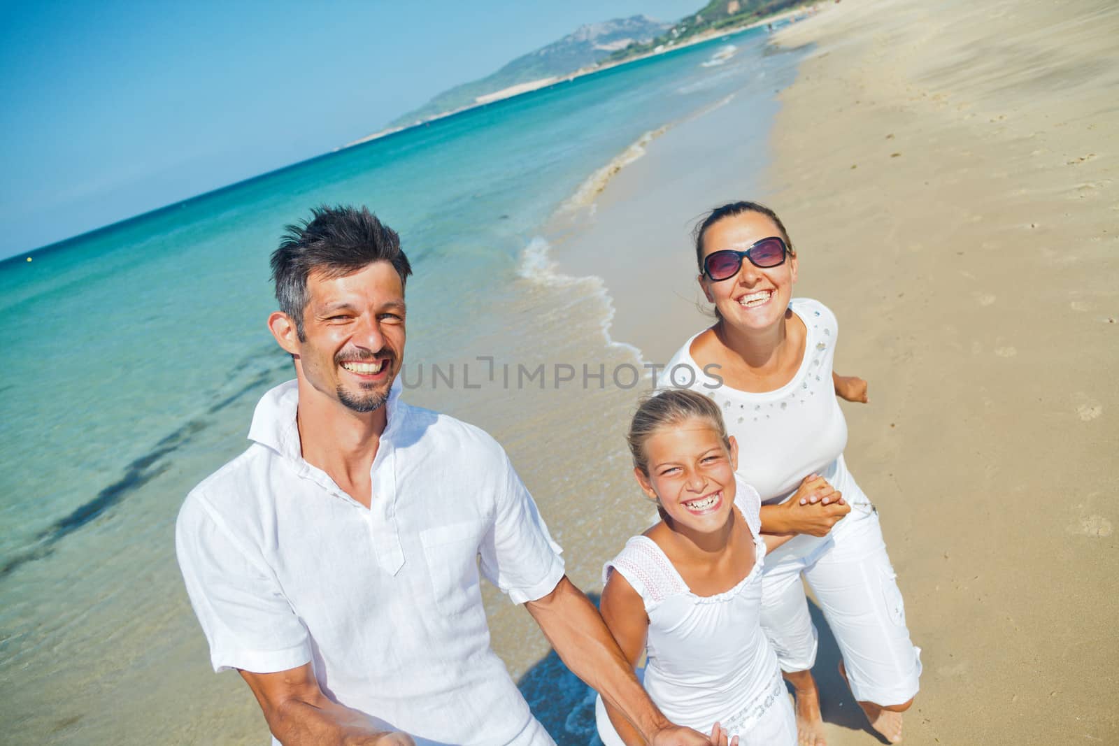 Photo of happy family running on the beach