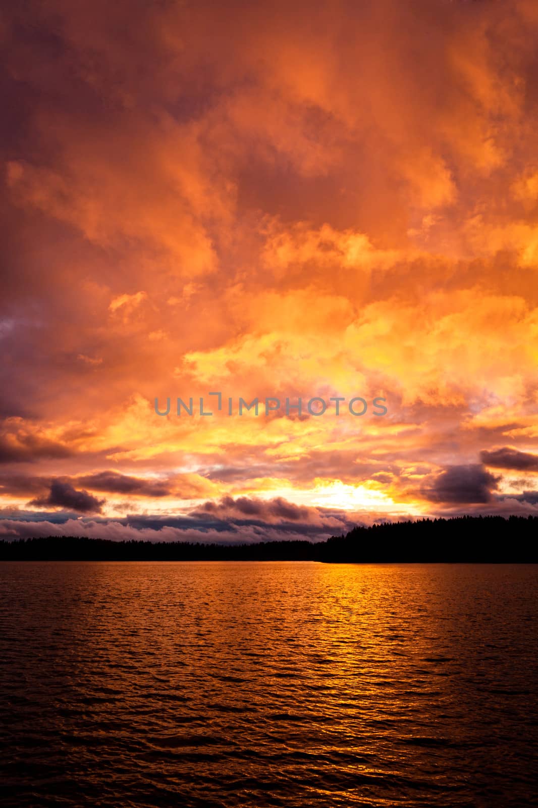 Dramatic fire red sunset over a lake by juhku