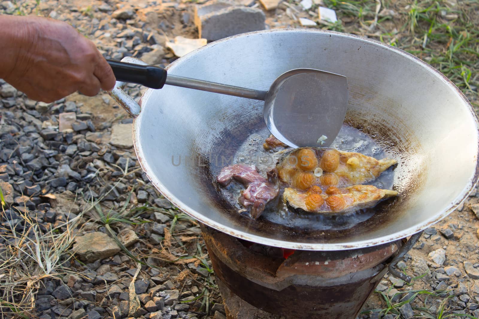 Fried fish in a frying pan by brazier ,Thai Cuisine.