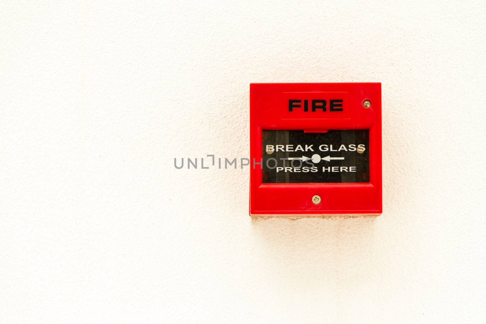 Red fire alarm switch on white concreat wall.